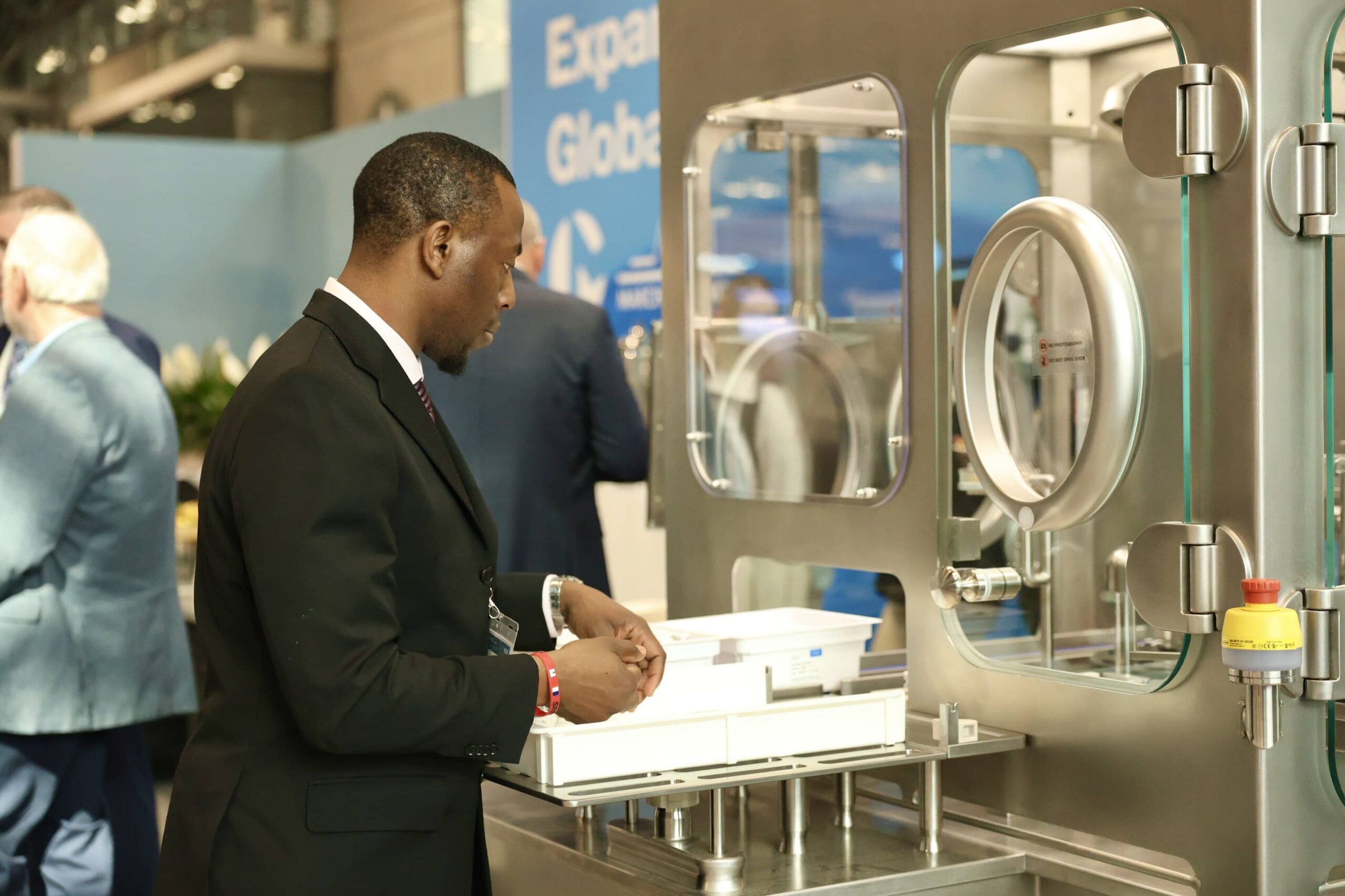 Attendees at INTERPHEX 2026 interacting with AST’s GENiSYS R modular aseptic fill-finish system.